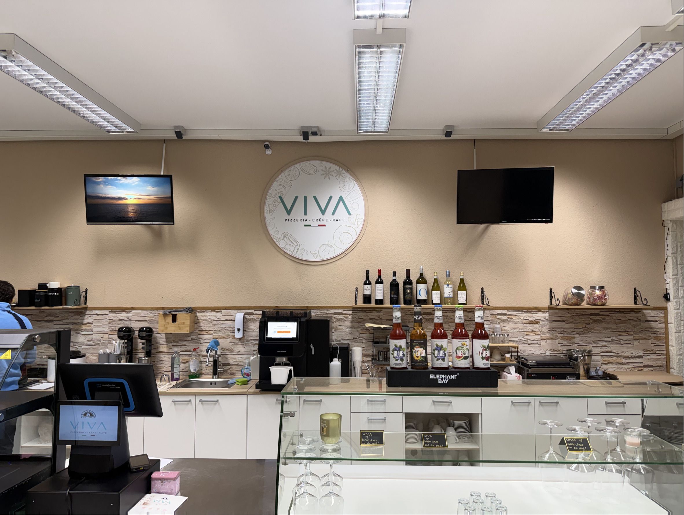 VIVA-Logo über der Theke und Kaffeemaschine